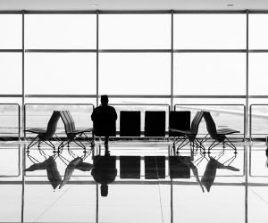 Black and White Photo of a Person Sitting in An Airline Terminal scaled